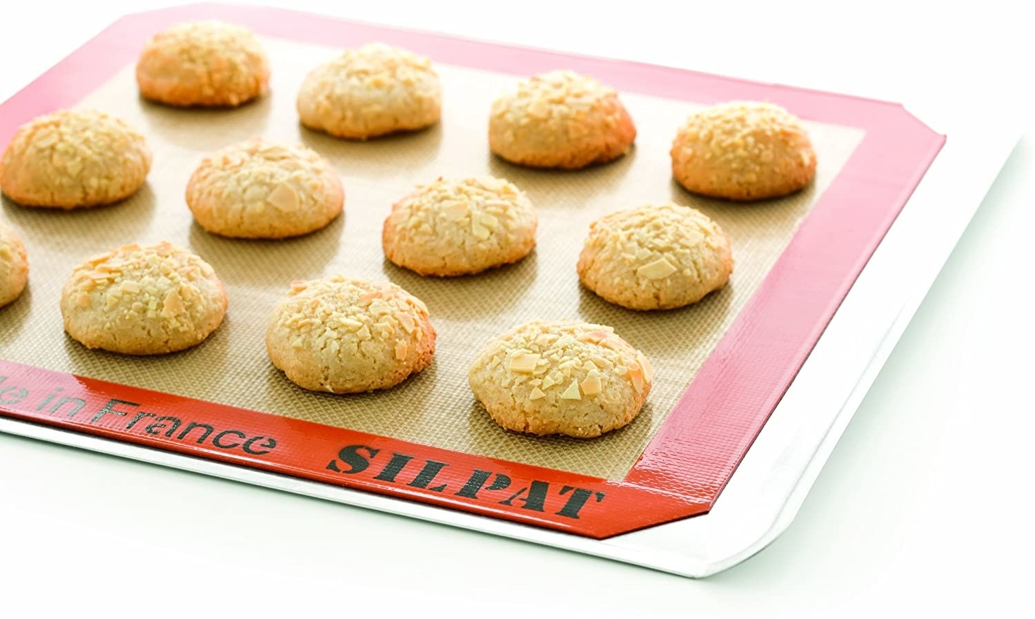 A silicone baking mat, with 12 delicious cookies on top, being used on a baking tray. 