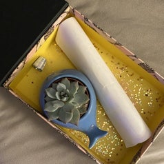A boxed filled with glitter, a note and a tiny plant