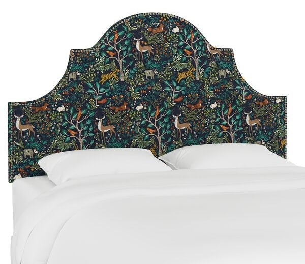 The headboard, which has a dark blue background and a forest print with deer, foxes, and trees