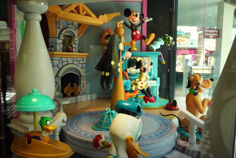 A Mickey, Goofy, Minnie, and Pluto statue waving to people in a living room window display