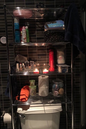 reviewer photo showing over-toilet storage shelf with several products and candles on it