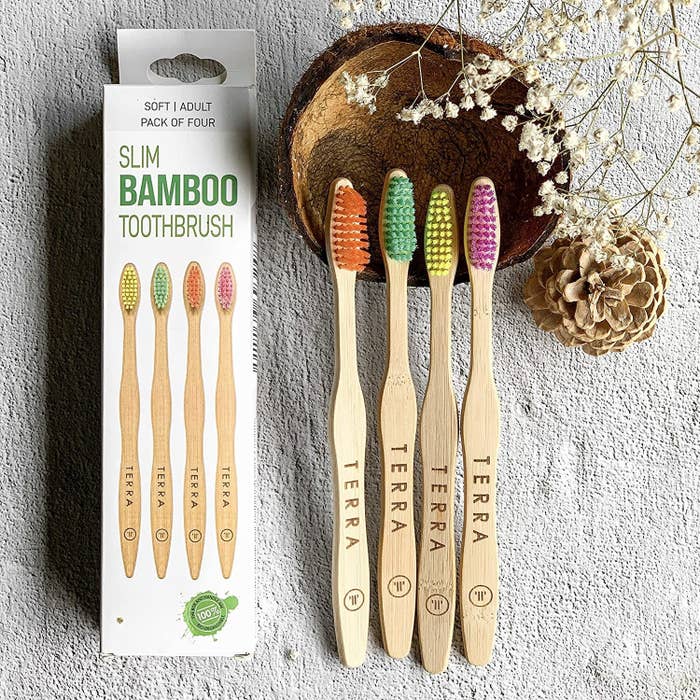A set of four bamboo toothbrushes with different coloured bristles.