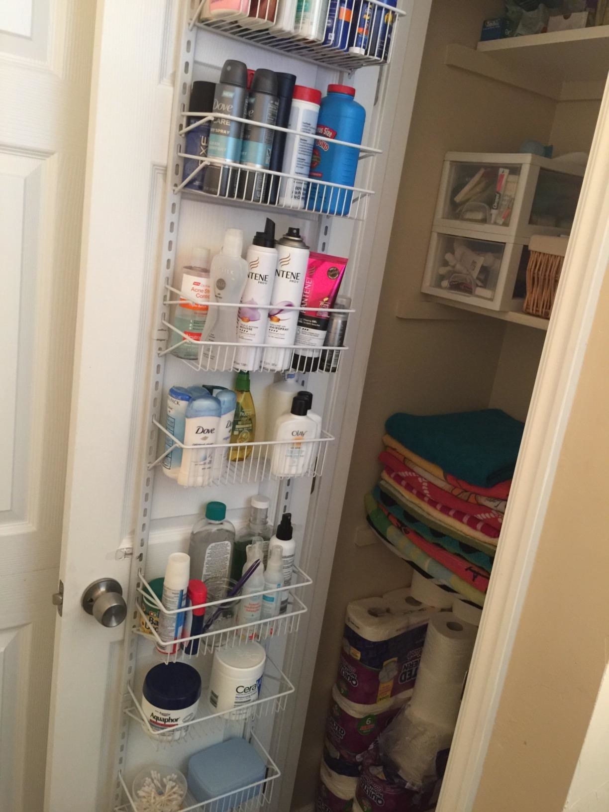 reviewer photo showing the door rack filled with toiletries on the back of their linen closet door 