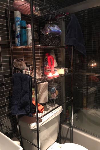 reviewer photo showing over-toilet storage shelf with several products and candles on it from a different angle 