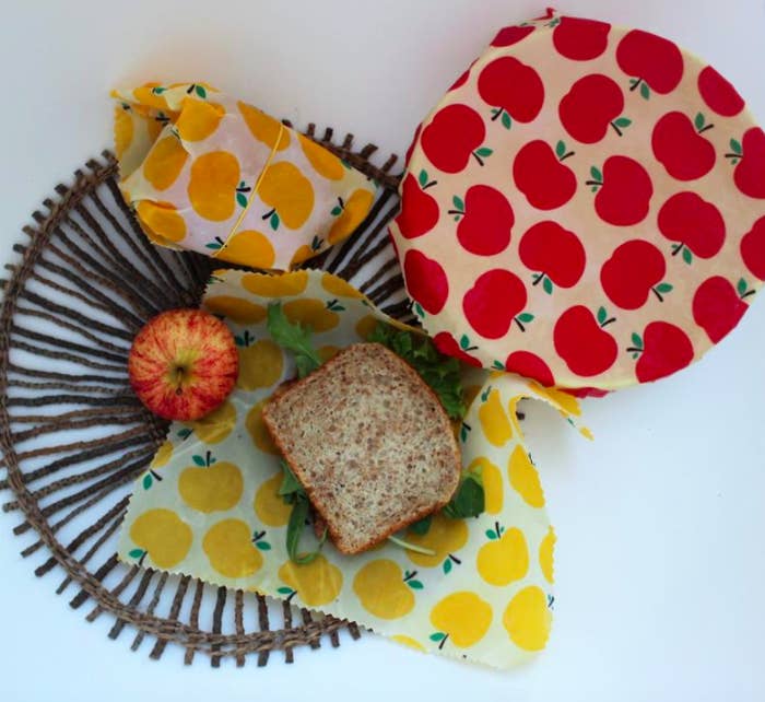 A trio of beeswax wraps next to bread and a fresh apple