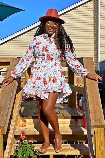 A reviewer wearing the long sleeve dress in white with red and blue flowers