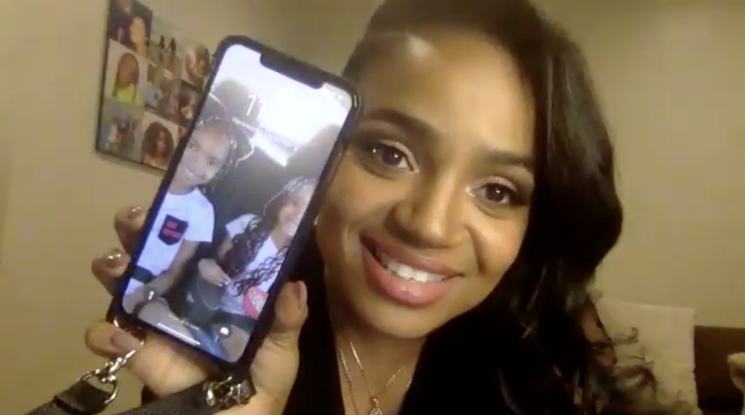 Kyla Pratt holding up her phone with a photo of her children on it
