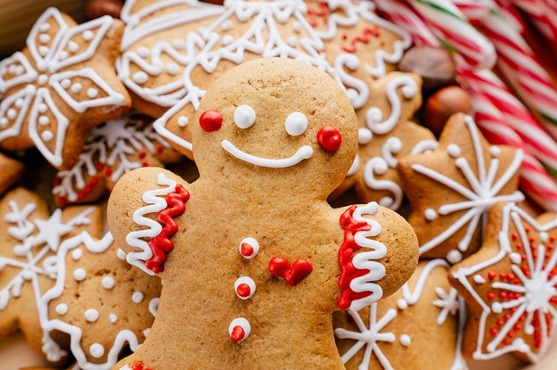 A smiling gingerbread man laying on top of a pile of gingerbread snowflakes