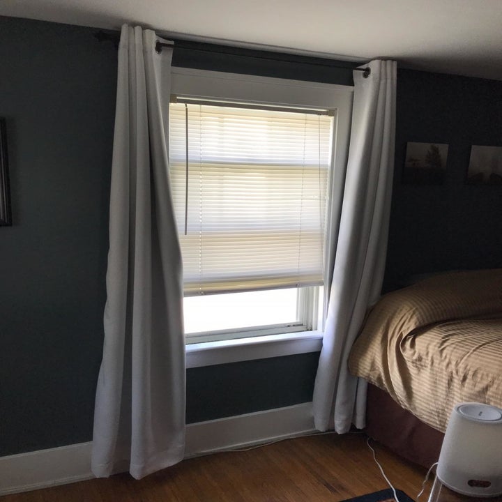 reviewer image of the nicetown blackout curtains hanging open from a window 