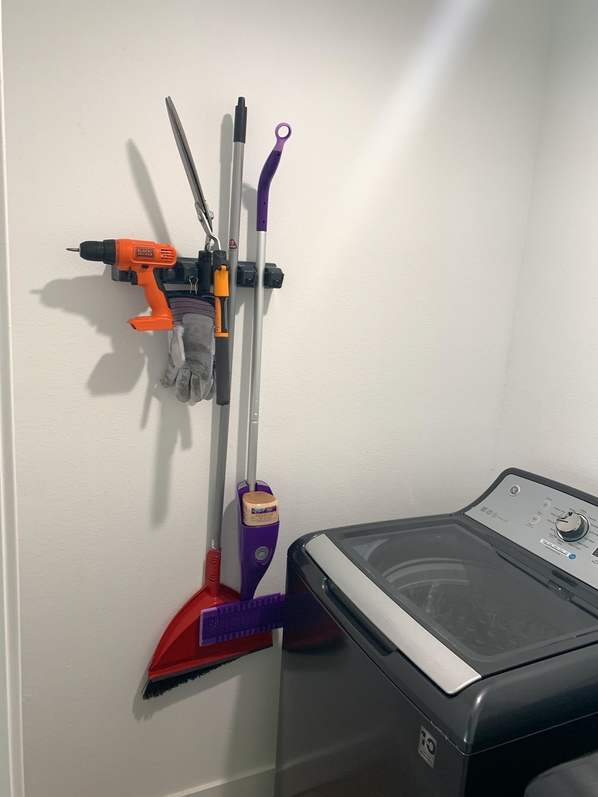 reviewer photo showing the organizer with a broom, Swiffer, and even a drill attached to it