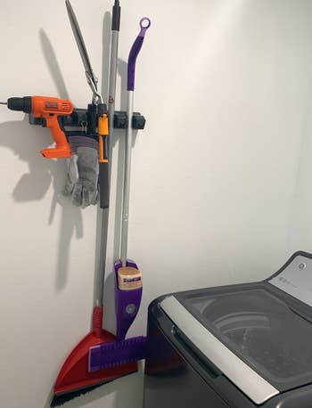 Reviewer photo showing the organizer with a broom, Swiffer, and even a drill attached to it