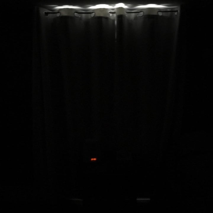 reviewer image of the nicetown blackout curtains hanging closed from a window, darkening a room 