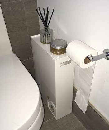 reviewer photo showing toilet paper stocker in their bathroom with a candle on it