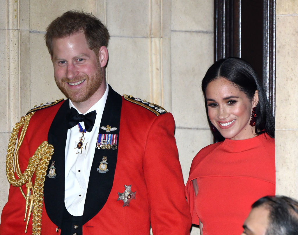 Prince Harry and Meghan Markle smiling for the cameras from a doorway 