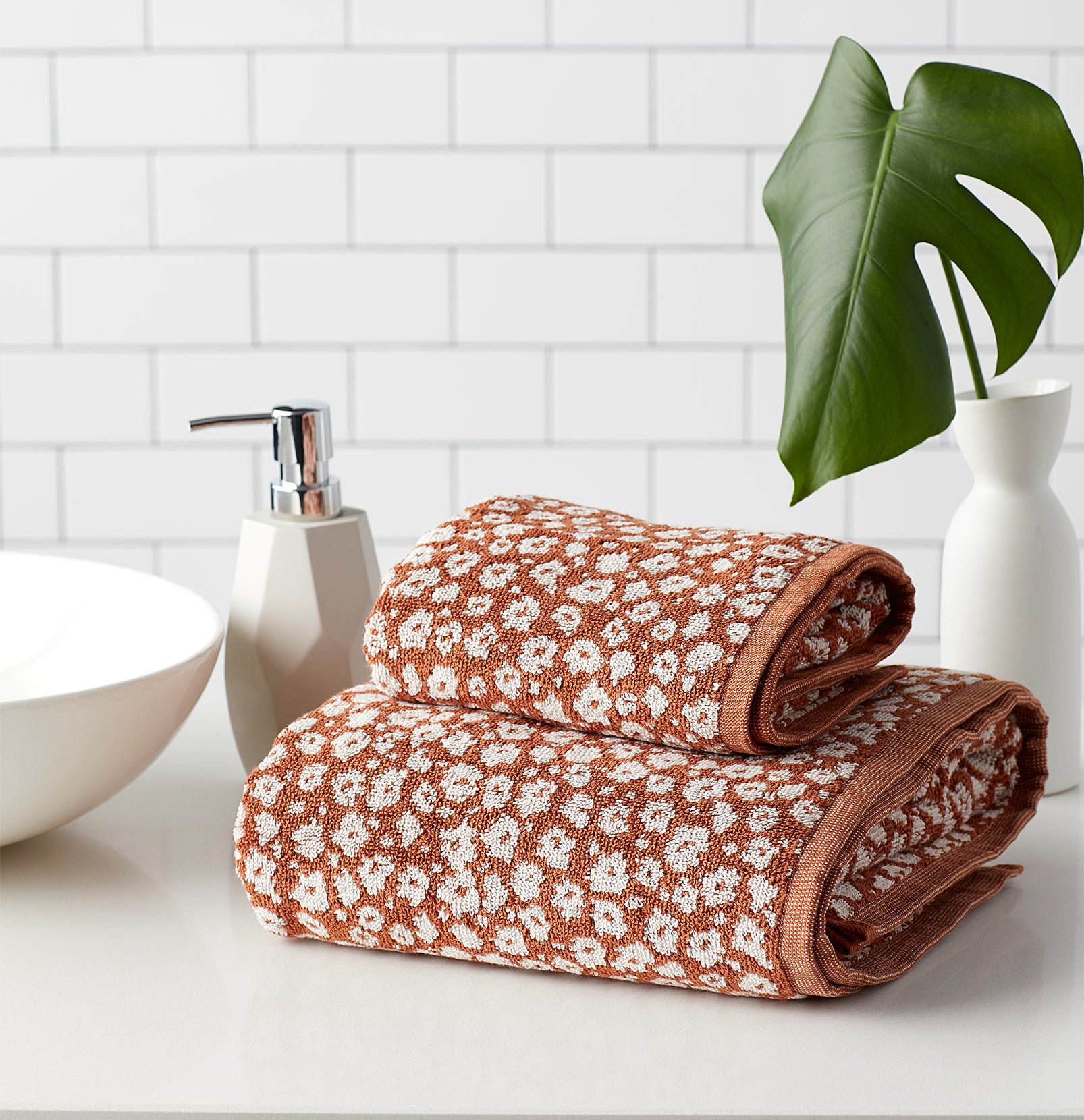 Two towels (one hand and one bath) stacked together in a clean bathroom
