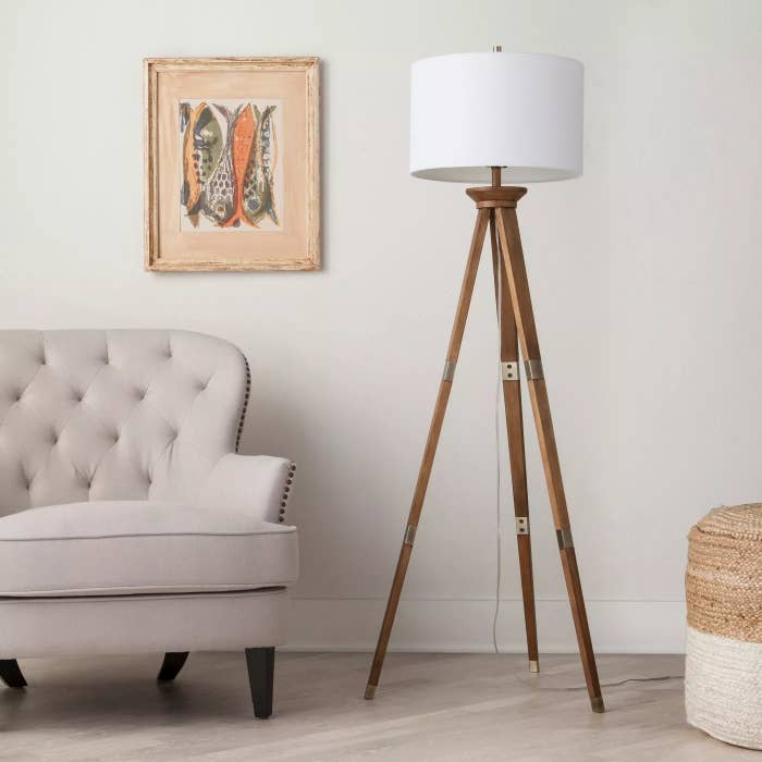 The tripod lamp with a round white lamp shade in a living room