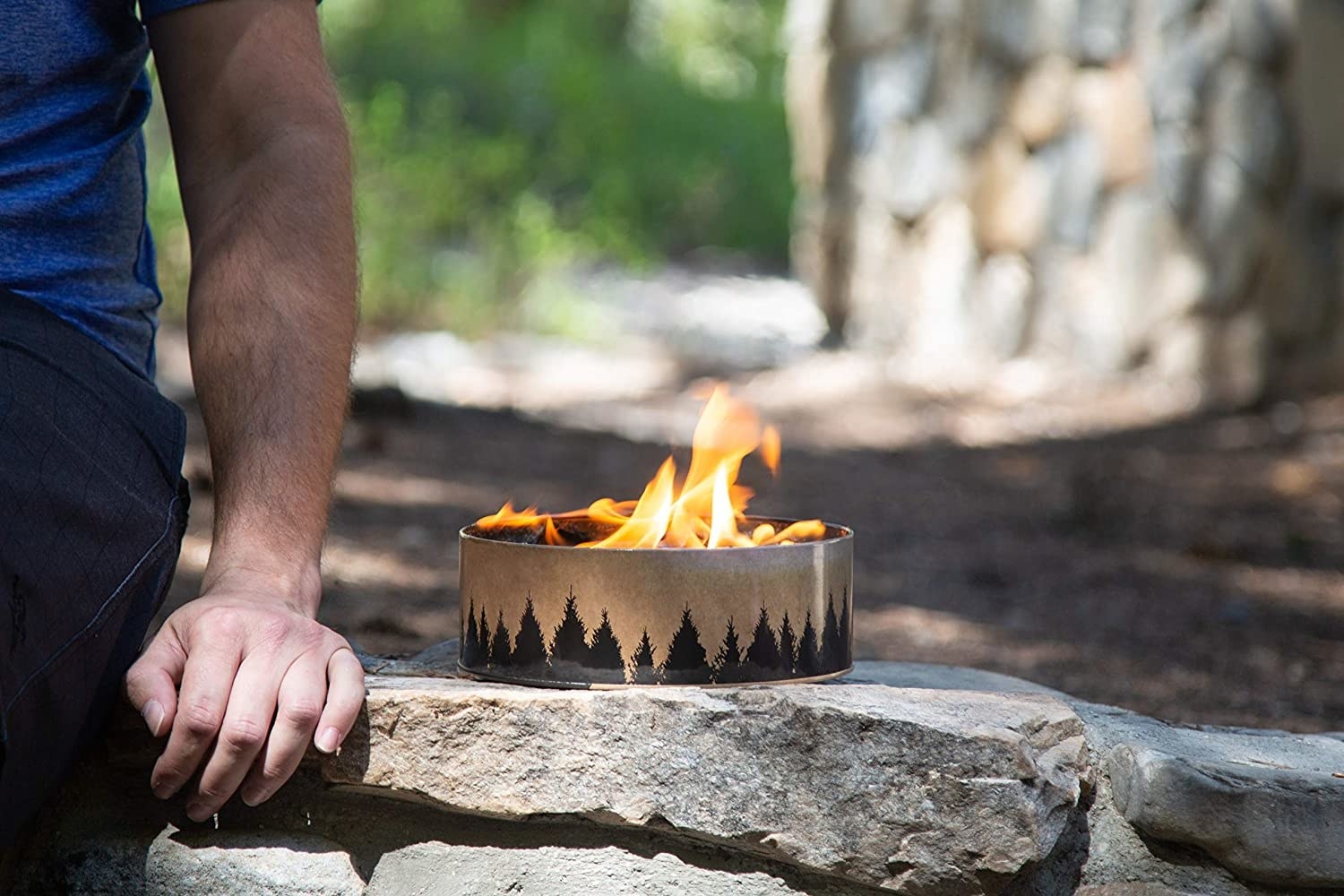 A person sitting next to the circular mini fireplace