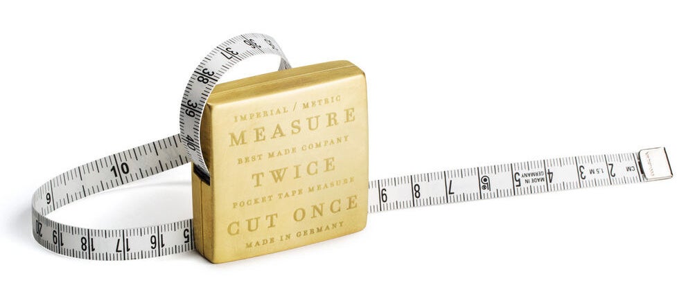 a brass measuring tape with teh words &quot;measure twice cut once&quot; engraved on it