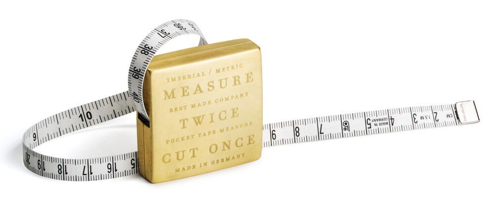 a brass measuring tape with teh words &quot;measure twice cut once&quot; engraved on it