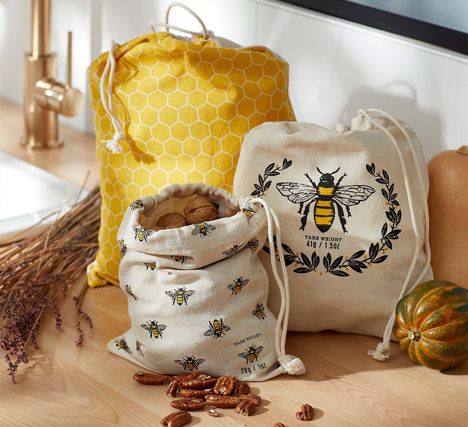 Three bee-themed bags with drawstrings on a counter 