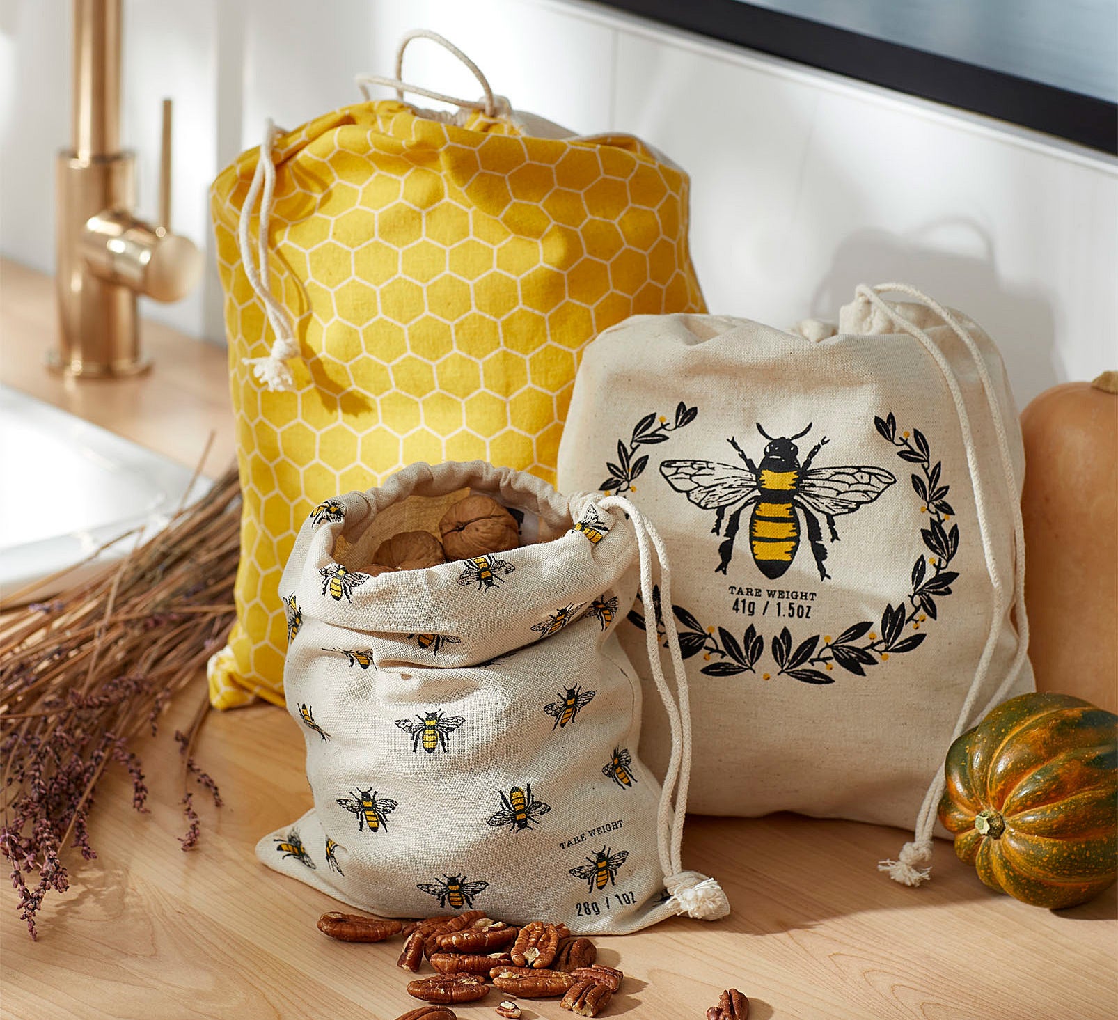 Three bee-themed bags with drawstrings on a counter