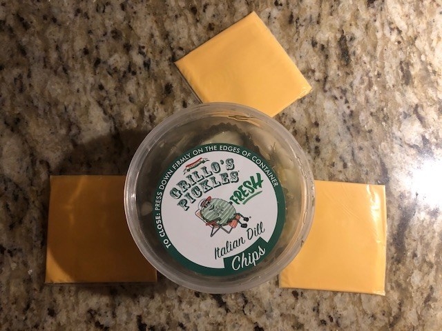 A container of pickles surrounded by Kraft cheese slices