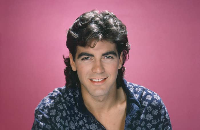 Head shot of George in a printed blue shirt with a pink background