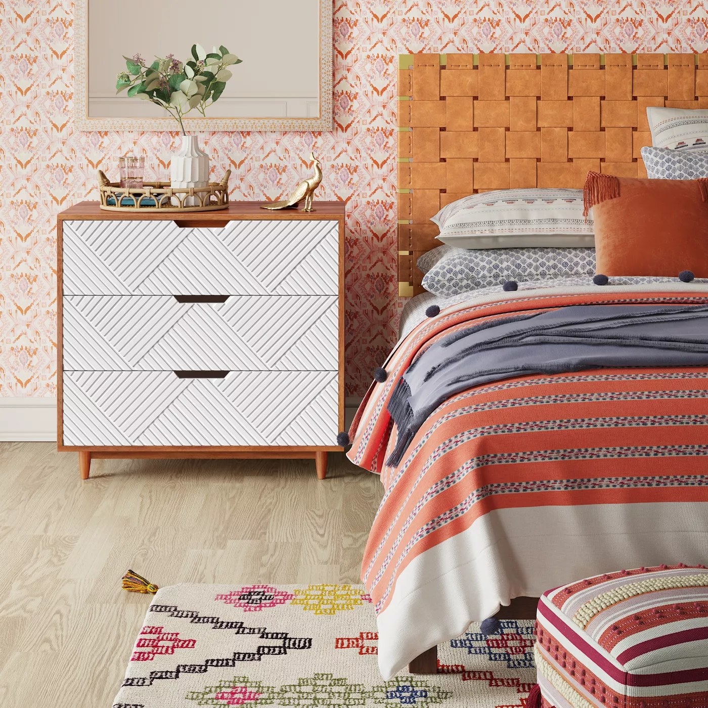 The dresser with geometrically textured white drawers next to a bed
