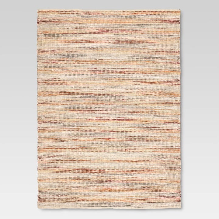 The multi-colored rug with beige, orange and red tones