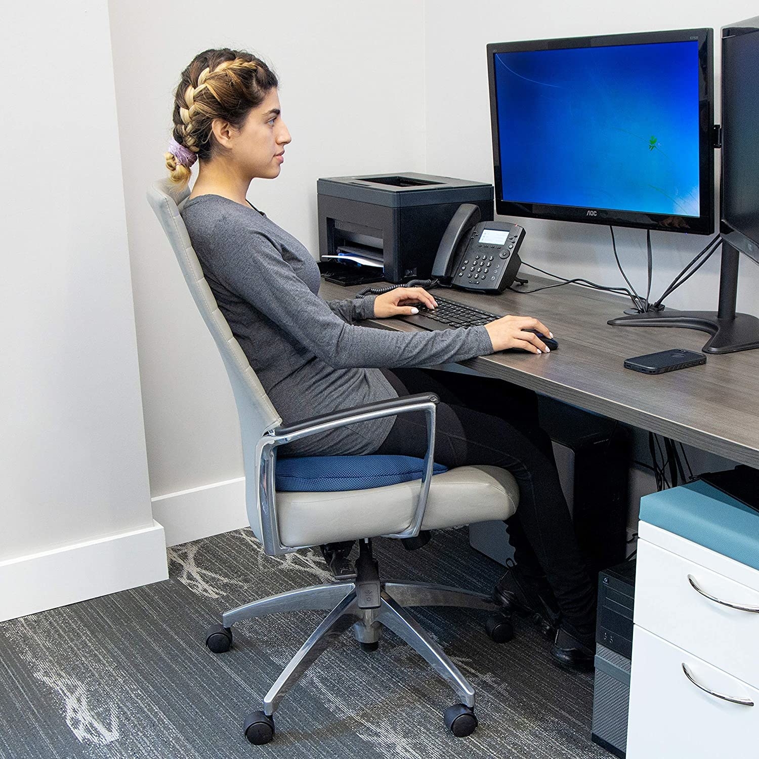 person sitting on the foam pillow on a chair at their desk on the computer