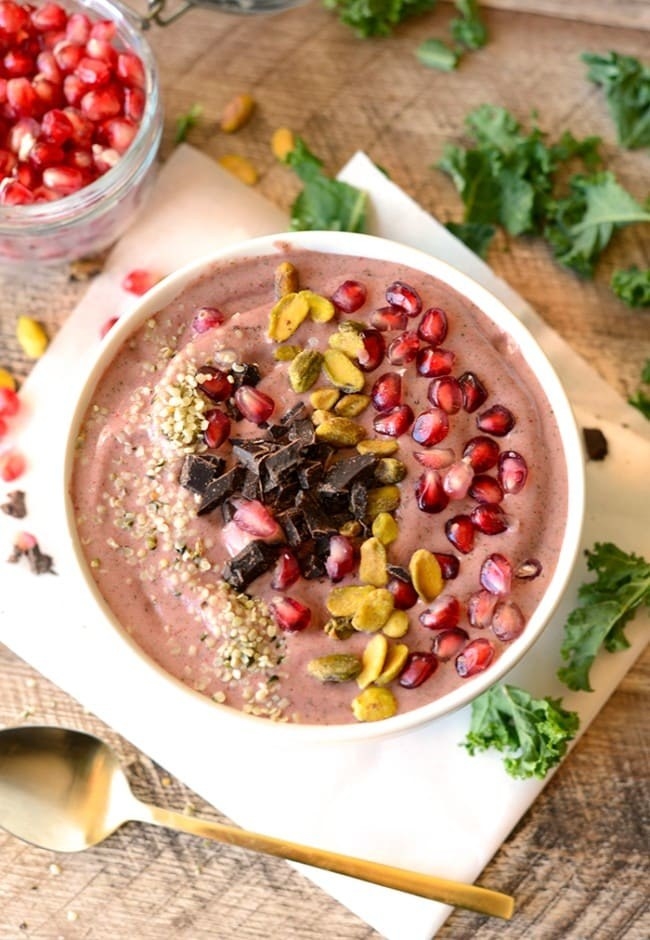 A pomegranate smoothie with cacao nib toppings in a bowl.