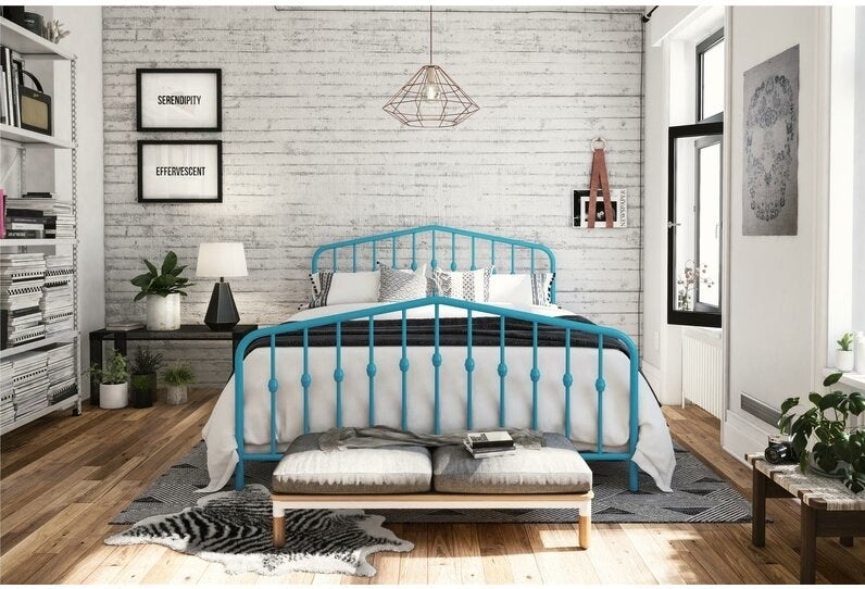 The bed in teal, with slatted wrought-iron-style bars inside a rounded frame at the head and foot of the bed