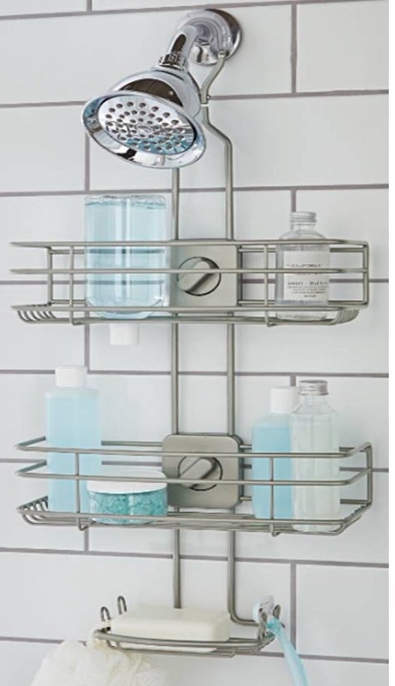 a brushed nickel shower caddy hung over a showerhead holding bottles on its two tiers and a soap bar in its soap dish tier