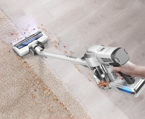 person using a tineco cordless vacuum to clean up crumbs on the floor