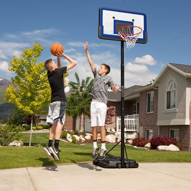 two teens playing basketball near a basketball hoop