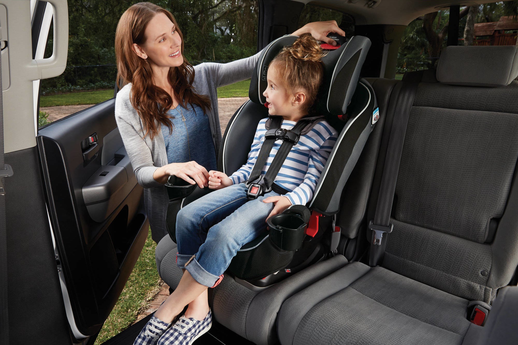 parent adjusting a car seat with a child in it