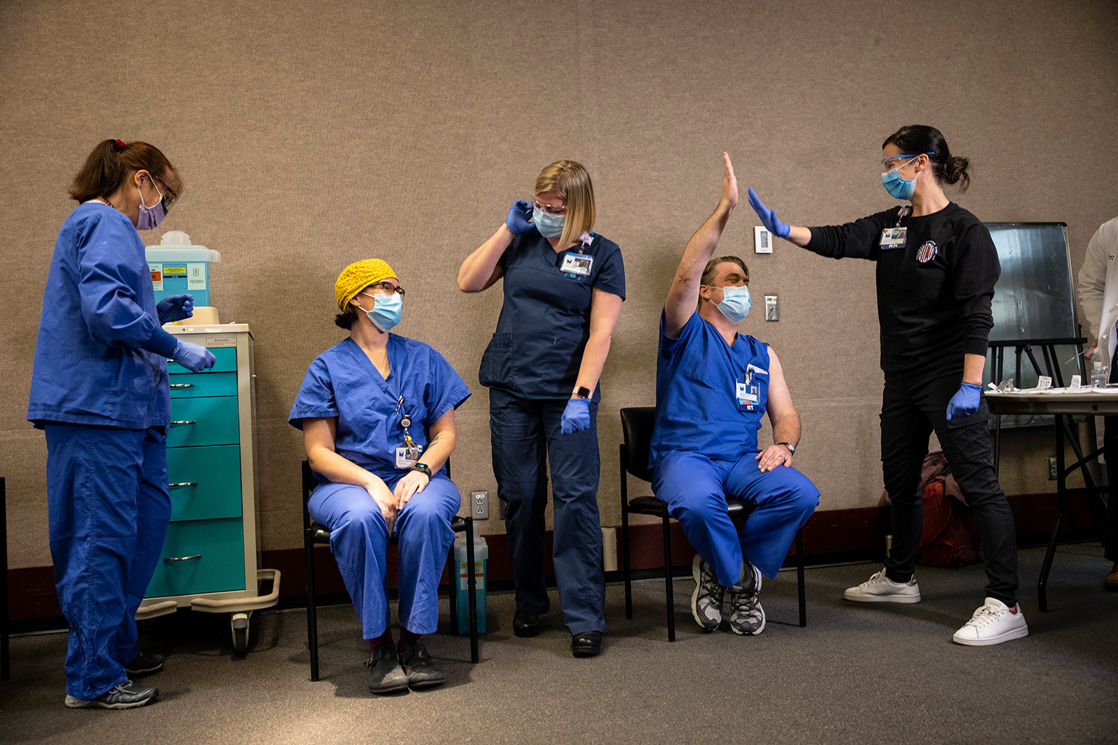 A group of people in hospital scrubs high five after being vaccinated against COVID-19