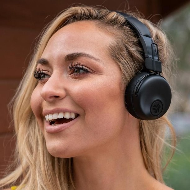 person wearing black on ear headphones while smiling