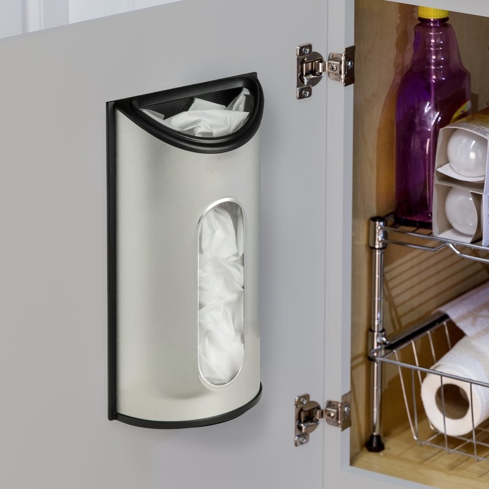 a stainless steel bag dispenser adhered to the inside of a cabinet