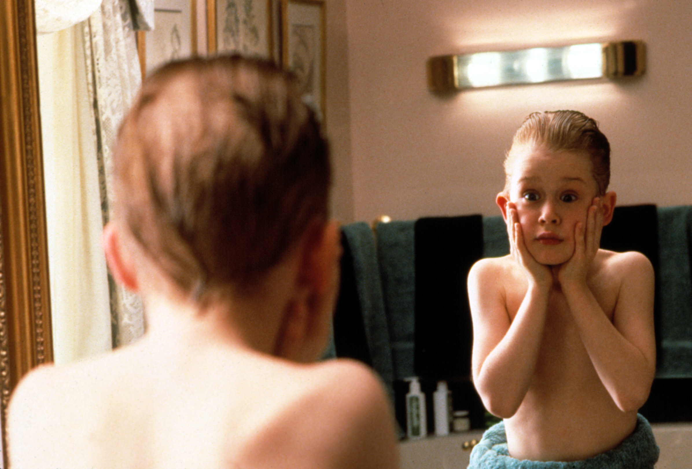 Kevin McCallister in "Home Alone" holds his face in shock as he looks in a mirror