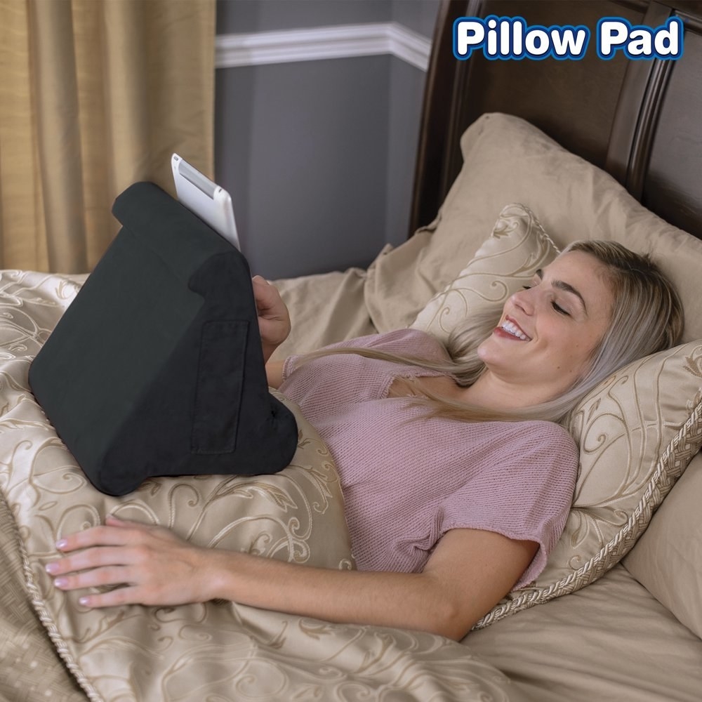 a model sitting in bed with their tablet resting on a pillow pad