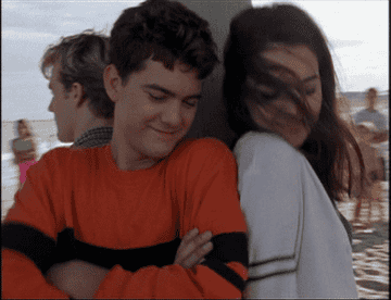 Gif of Dawson&#x27;s Creek Season 1 credits; Joey and Pacey playfully shrug their shoulders together on the beach; Dawson can be seen alone behind them 