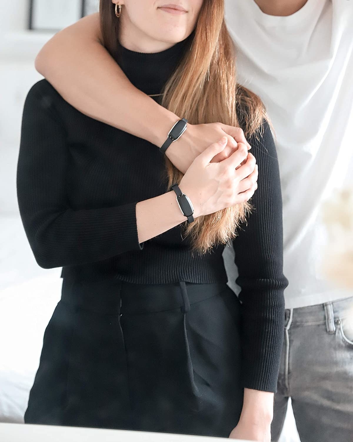 Two models wearing the black bracelets and holding hands