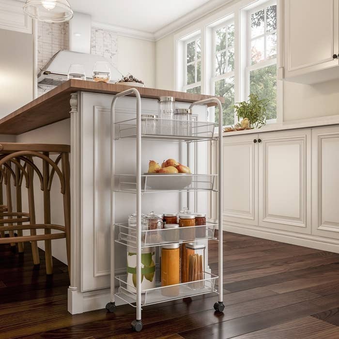 a 4-tiered rolling cart holding pantry essentials next to a kitchen island