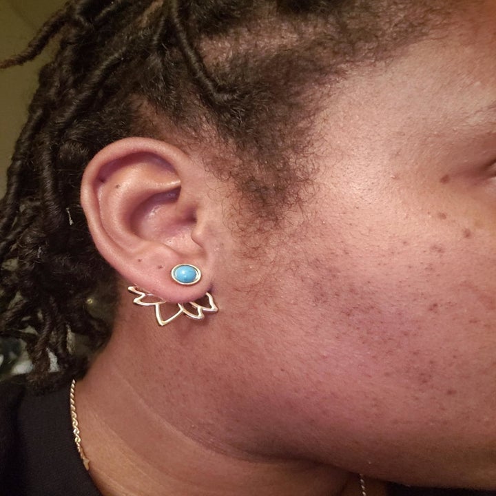 A reviewer wearing the earrings in gold. The back part sits behind the earlobe