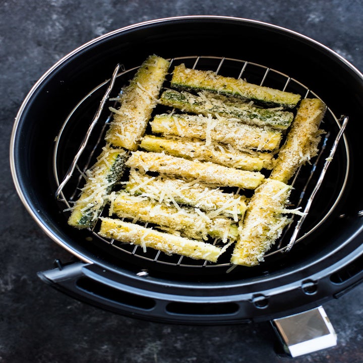 Zucchini fries in the basket of an air fryer.