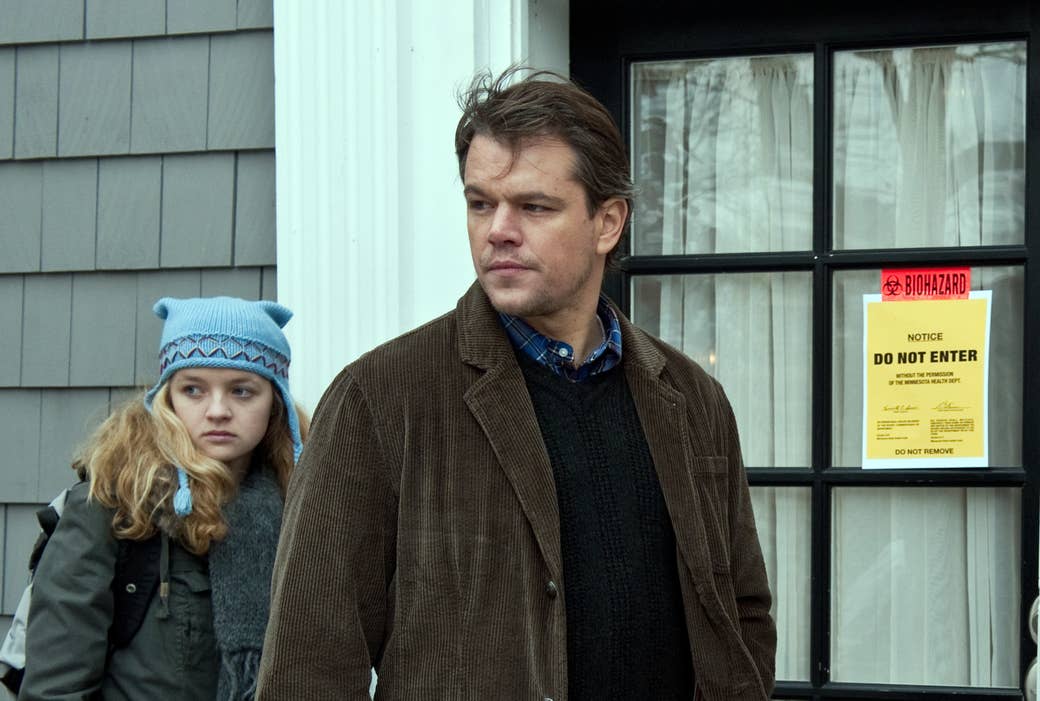 A still from the movie &quot;Contagion&quot; shows a blonde daughter in a scarf and knitted cap standing behind her father, in a corduroy jacket, both looking to their right; behind them is a &quot;biohazard: do not enter&quot; sign