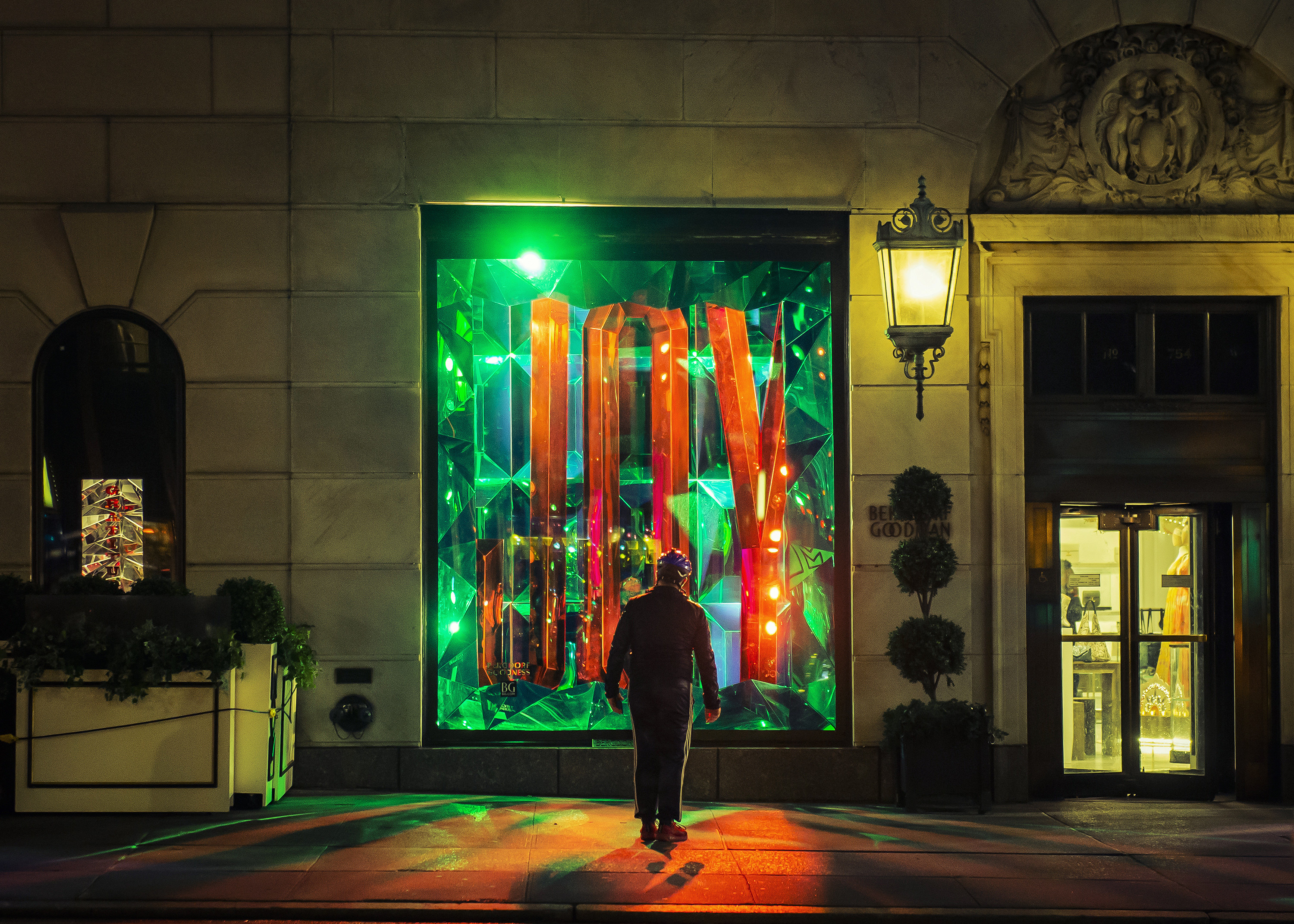 A lone person looking at a Christmas display at night