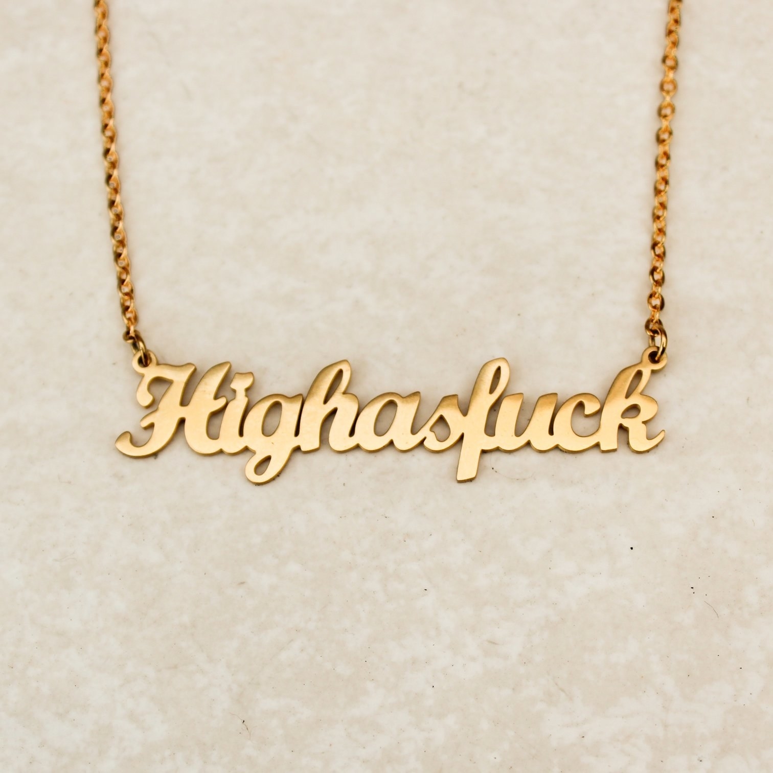 An image of a gold necklace that says, "Highasfuck."