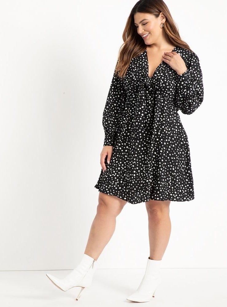 model wears tie front black dotted dress with white booties